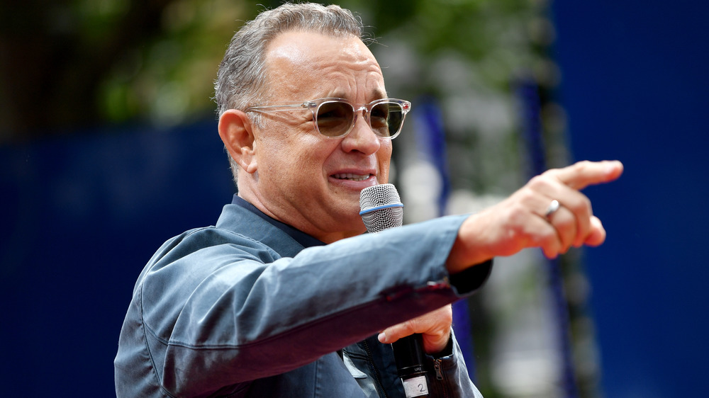 Tom Hanks holding microphone and pointing