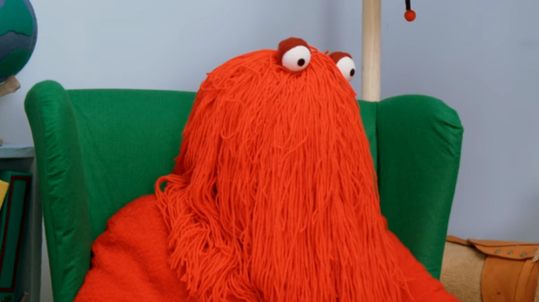 Red Guy sits in a chair