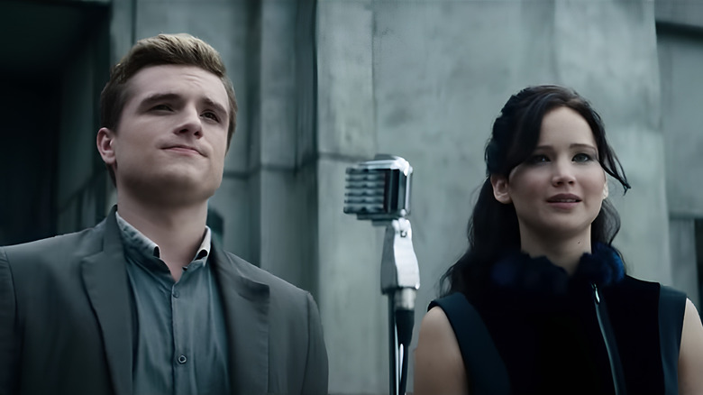 Peeta and Katniss standing in front of microphone