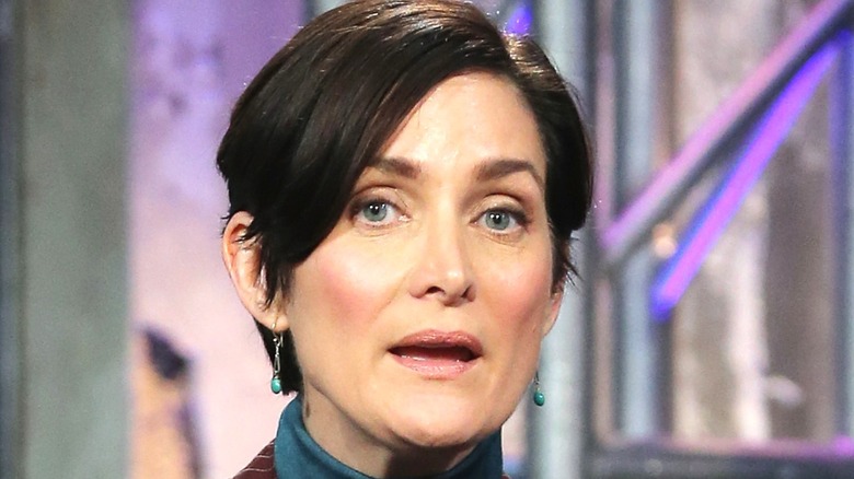 Carrie-Anne Moss with short hair and earrings