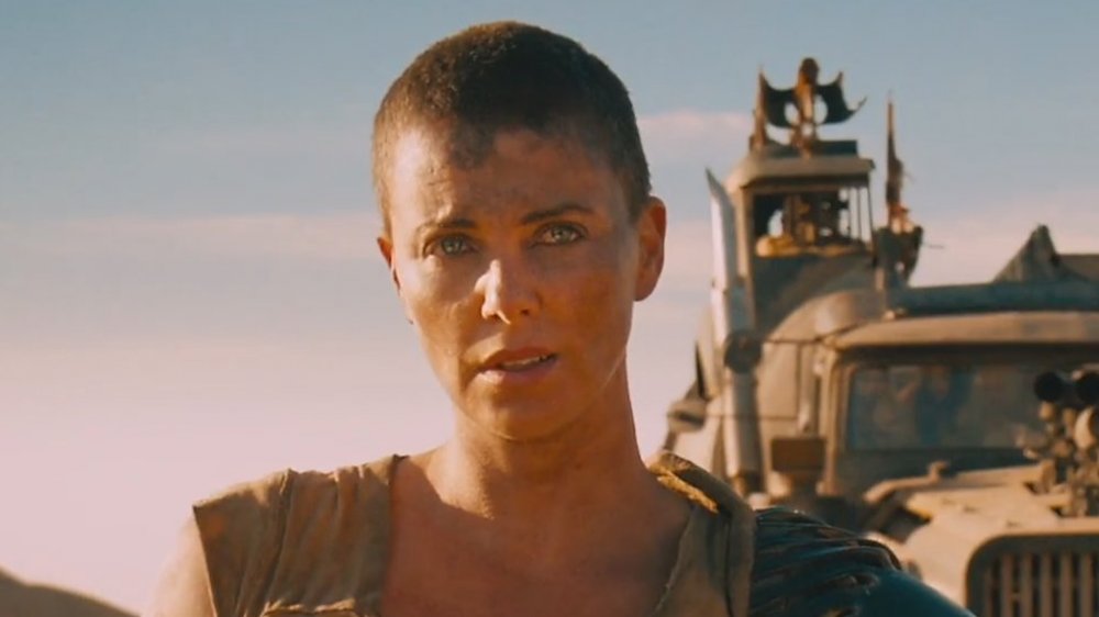 Charlize Theron as Furiosa, standing in front of truck in Mad Max: Fury Road